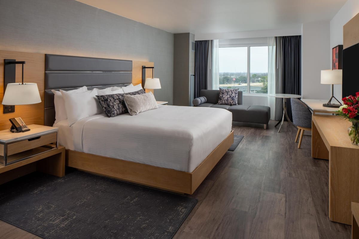 Habitación de hotel moderna con una cama grande, mesitas de noche, un escritorio y vistas a la ciudad.