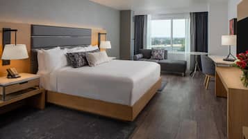 Une chambre d’hôtel moderne, dotée d’un grand lit, de tables de chevet, d’un bureau et offrant une vue sur la ville.