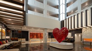 Un vestíbulo amplio con mostrador de recepción, zona de estar y una gran escultura de corazón rojo.