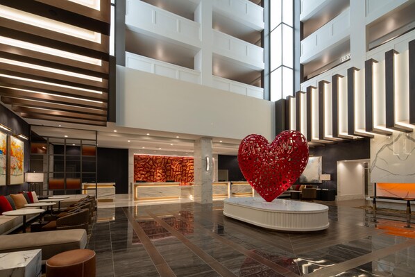 A spacious lobby with a reception desk, seating area, and a large red heart sculpture.