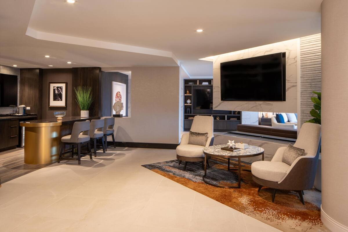 Una sala de estar moderna con barra, asientos y un televisor grande.
