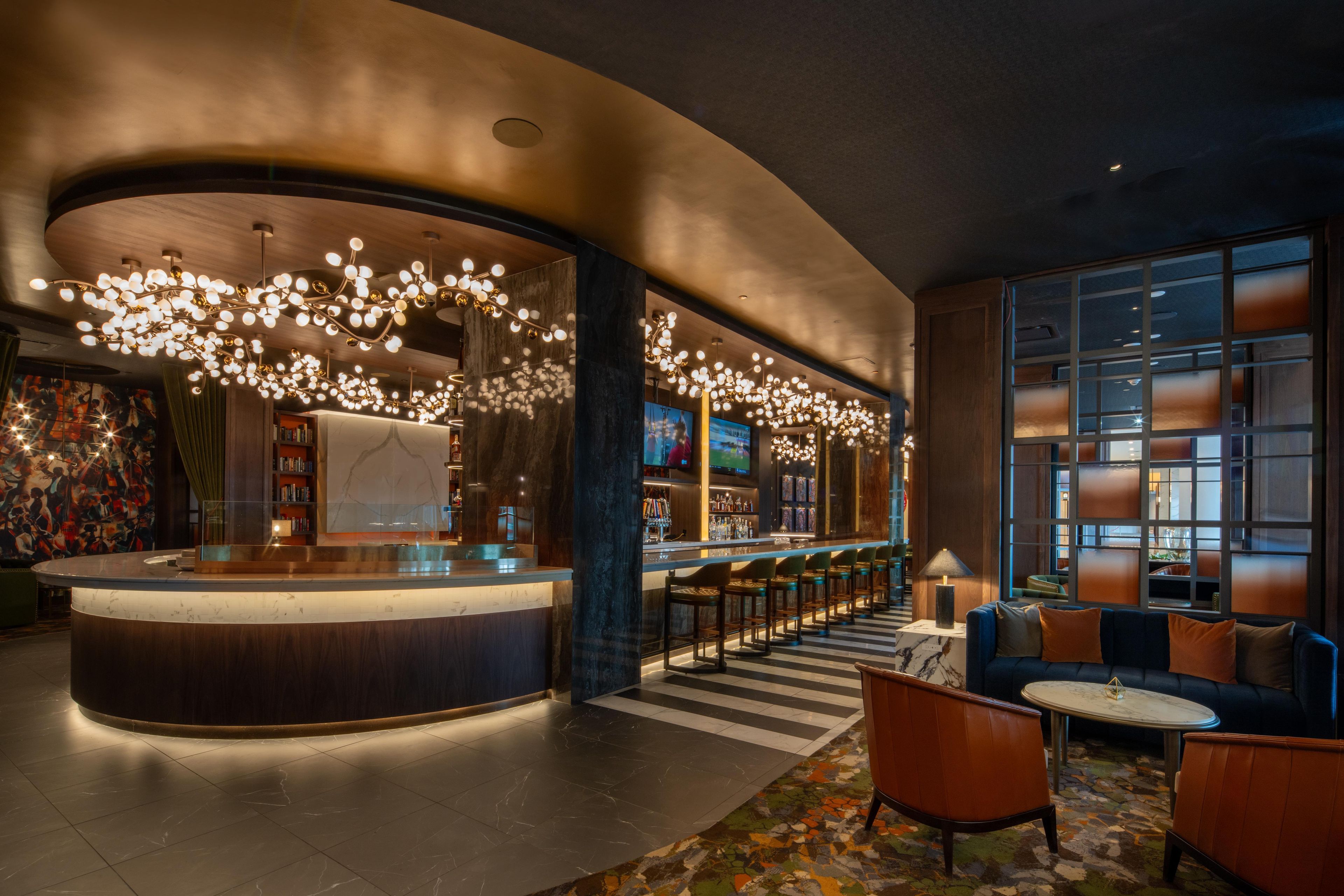 Eine moderne Lobby mit einer gebogenen Rezeption, einer Bar, Sitzgelegenheiten und großen Fenstern.