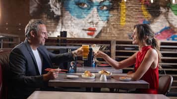 Un homme et une femme sont assis à une table dans un restaurant, avec une fresque murale en arrière-plan.