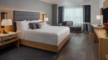 A modern hotel room with a large bed, bedside tables, a desk, and a chair.