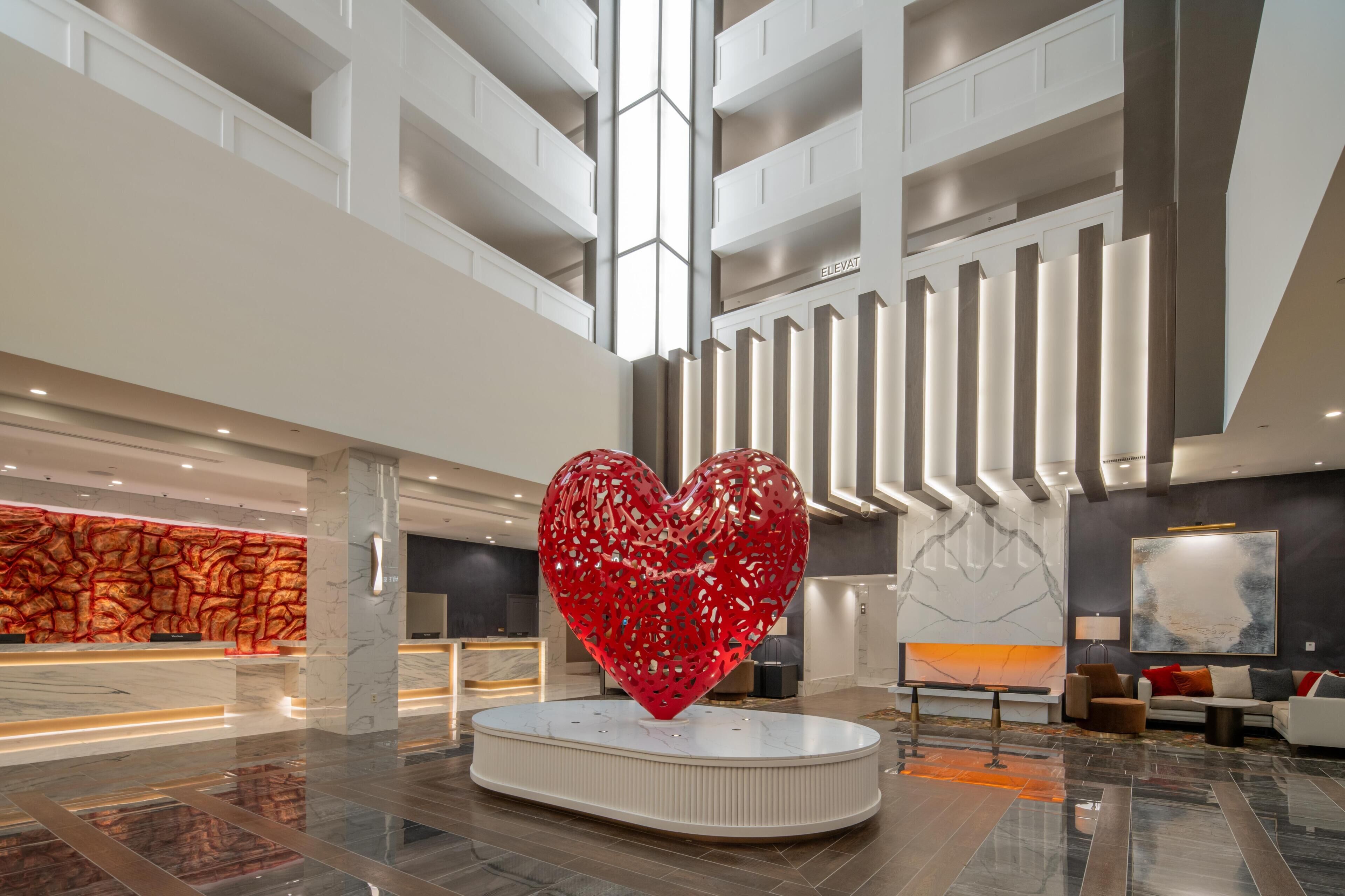 A spacious lobby with a large heart-shaped sculpture, a reception desk, and a modern interior design.