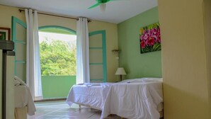 A room with a bed, a window with curtains, a painting, and a ceiling fan. - Hotel Caledônia Inn (Nova Friburgo)