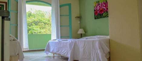 A room with a bed, a window with curtains, a painting, and a ceiling fan.