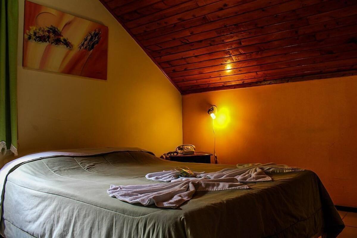 Ein Zimmer mit einem Bett, einem Nachttisch und einer Wandleuchte.