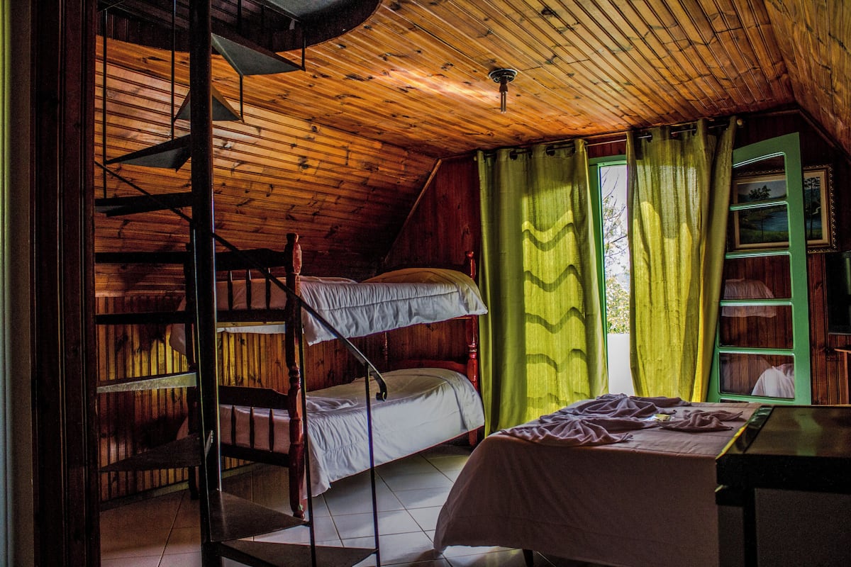 Ein Zimmer mit Etagenbett, Schreibtisch und einem Fenster mit Vorhängen.