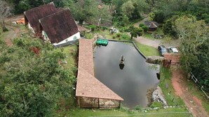 A large pond with a gazebo and a small house in a lush, green area. - Hotel Caledônia Inn (Nova Friburgo)