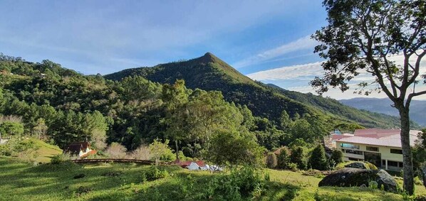 Un paisaje montañoso con un edificio de techo rojo, rodeado de vegetación exuberante y árboles.