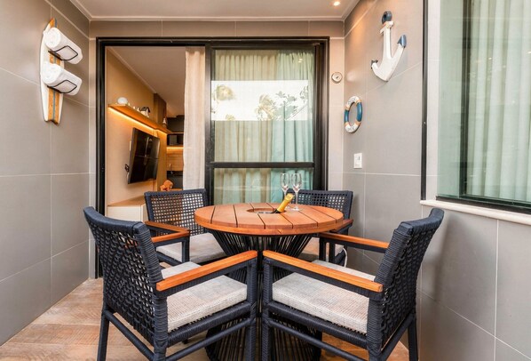 A round wooden table with four chairs, a small bottle, and two glasses. - On the sand with private heated pool (Ipojuca)