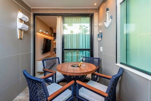 Un comedor con una mesa redonda de madera, sillas de mimbre, un televisor y una ventana con cortinas.