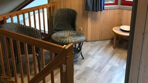 Un intérieur en bois avec un escalier, un coin repas et une fenêtre avec des rideaux.
