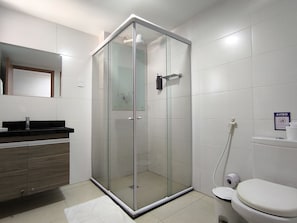 A modern bathroom with a glass shower enclosure, a toilet, and a sink with a mirror above it.