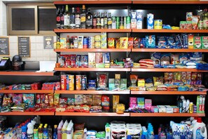 Una tienda con estantes llenos de diversos productos, como aperitivos, bebidas y artículos del hogar.