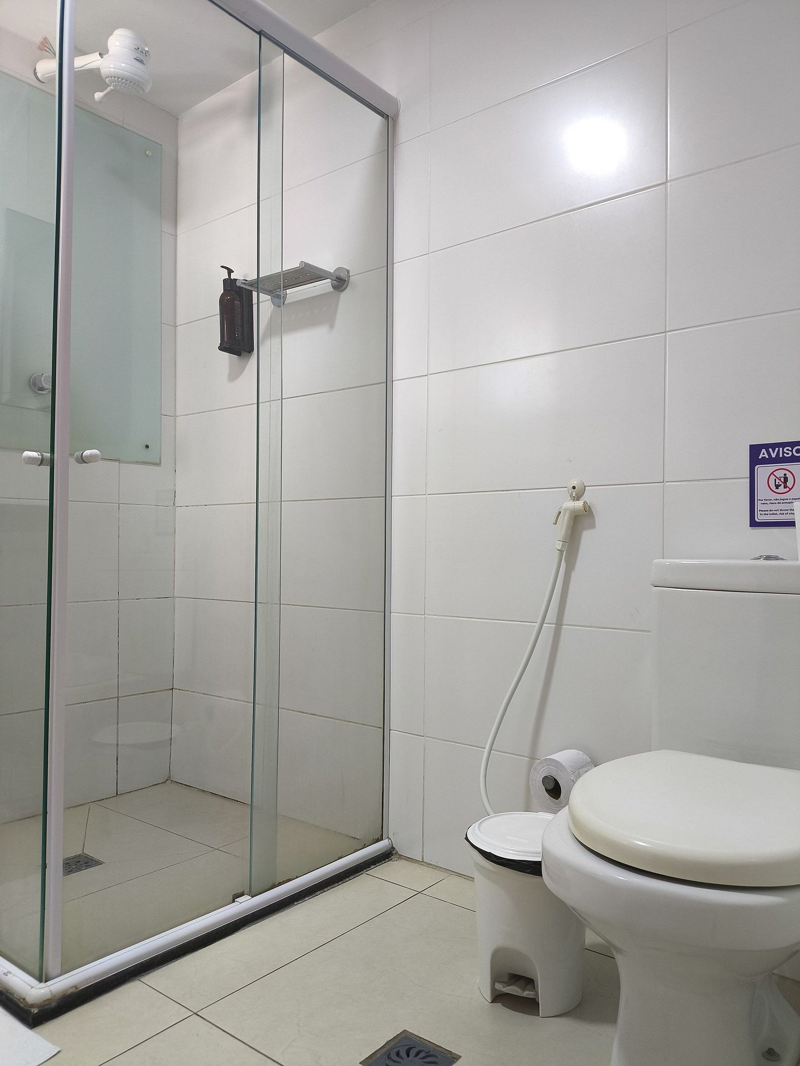 A bathroom with a glass-enclosed shower, a toilet, and a sink.