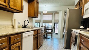 Cocina con armarios de madera, lavavajillas, refrigerador y piso estampado.
