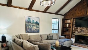 Una sala de estar con sofá modular, una mesa de centro, televisor y chimenea.