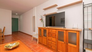 A room with a wooden cabinet, a television, and a dining table with a decorative bowl.