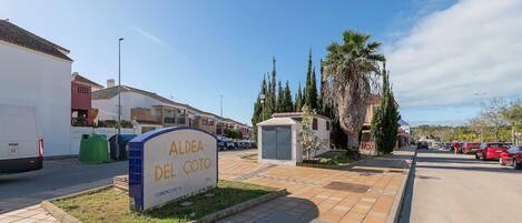 A residential area with a sign for "Aldea Del Coto" and a small utility shed.