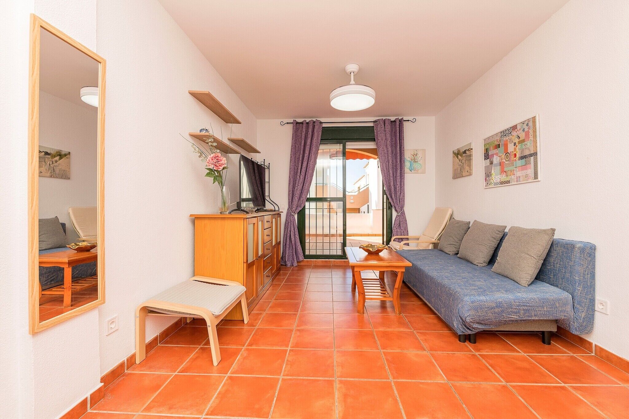 En kompakt opholdsstue med sofa, lille bord, bænk og skab.