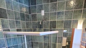 Ein Badezimmer mit einer Duschkabine, einer weißen Toilette und einem Waschbecken mit Spiegel.