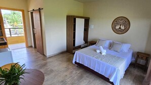 Ein Schlafzimmer mit Bett, Kleiderschrank, Spiegel, einem kleinen Tisch und einer Zimmerpflanze.