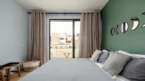 Un dormitorio con una cama grande, vistas de la ciudad a través de un ventanal corredero y una pared con espejos circulares.