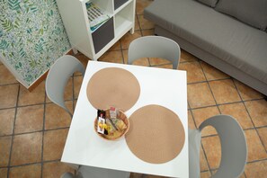Ein weißer Tisch mit zwei gewebten Tischsets, einem Korb mit Gegenständen und zwei grauen Stühlen.
