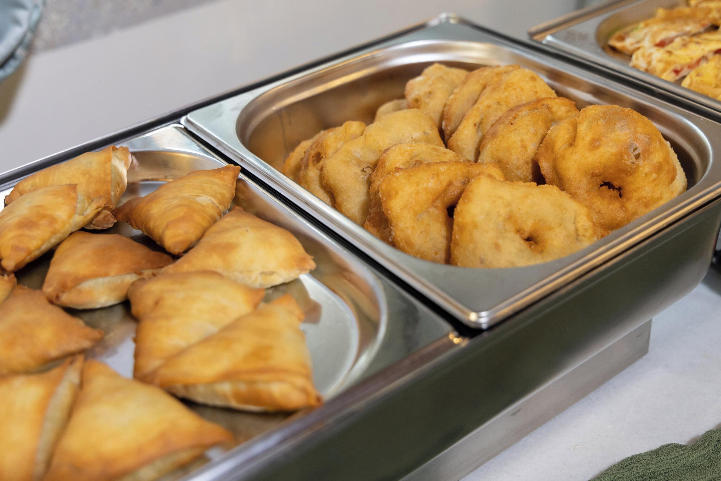 A buffet with various baked items, including pastries and possibly some fried foods.