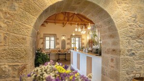 A stone-walled kitchen with an arched ceiling, a central island, and hanging light fixtures.