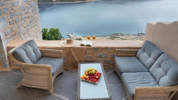 Un balcon agrémenté de meubles en osier, une table avec des fruits et une vue sur la mer.