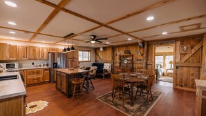 A rustic kitchen with wooden cabinets, a central island, and a dining area with a chandelier.