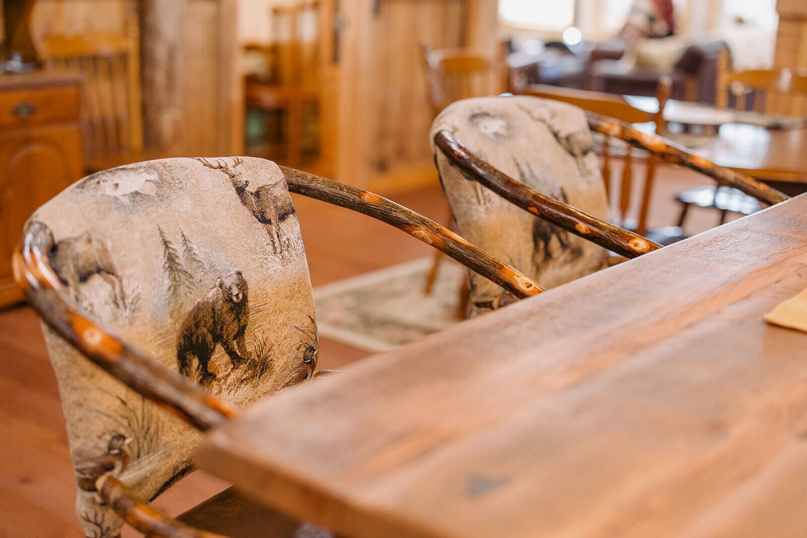 A wooden dining table with chairs that have animal prints.