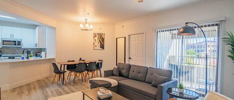 Una sala de estar moderna con un sofá gris, una mesa de centro y un comedor con sillas y una mesa.