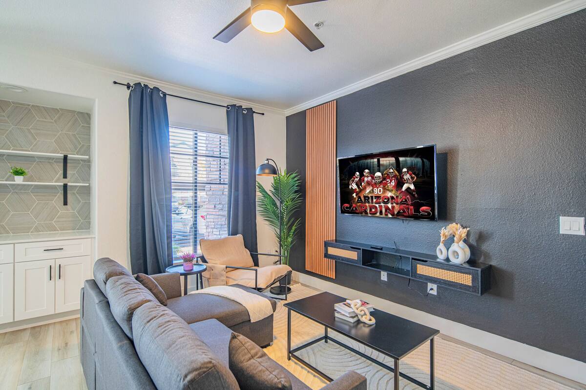 Een moderne woonkamer met een bank, salontafel en een aan de muur bevestigde televisie.