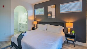 A bedroom with a large bed, two bedside tables with lamps, a headboard, and artwork on the wall. - ROVE LIVING/KB - Zone (Glendale)