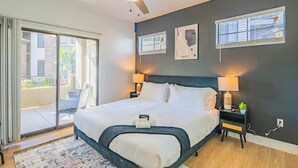 A bedroom with a large bed, two bedside lamps, a ceiling fan, and a view through a sliding glass door to an outdoor area. - ROVE LIVING/KB - Zone (Glendale)
