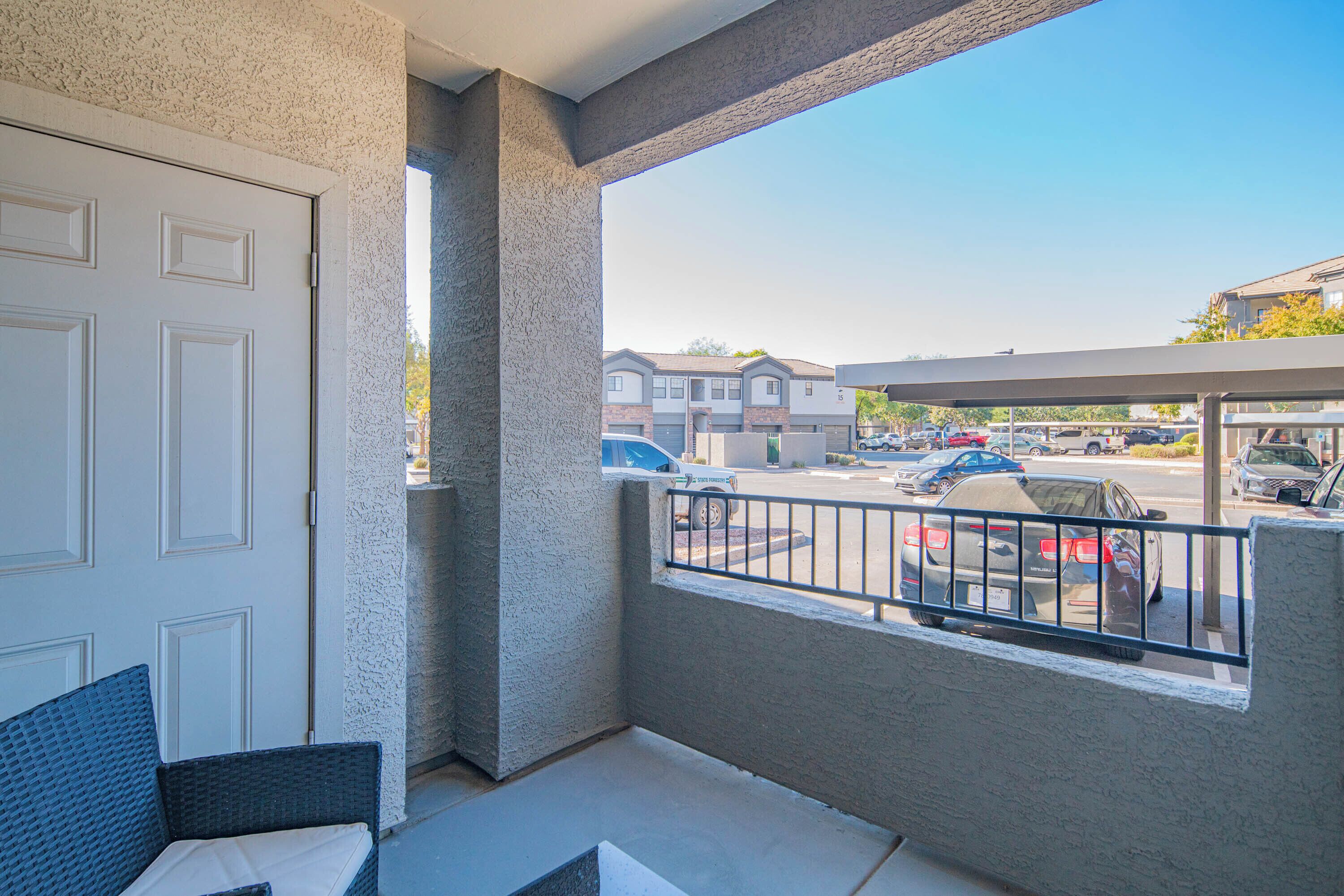 A balcony with a view of a parking lot and buildings.
