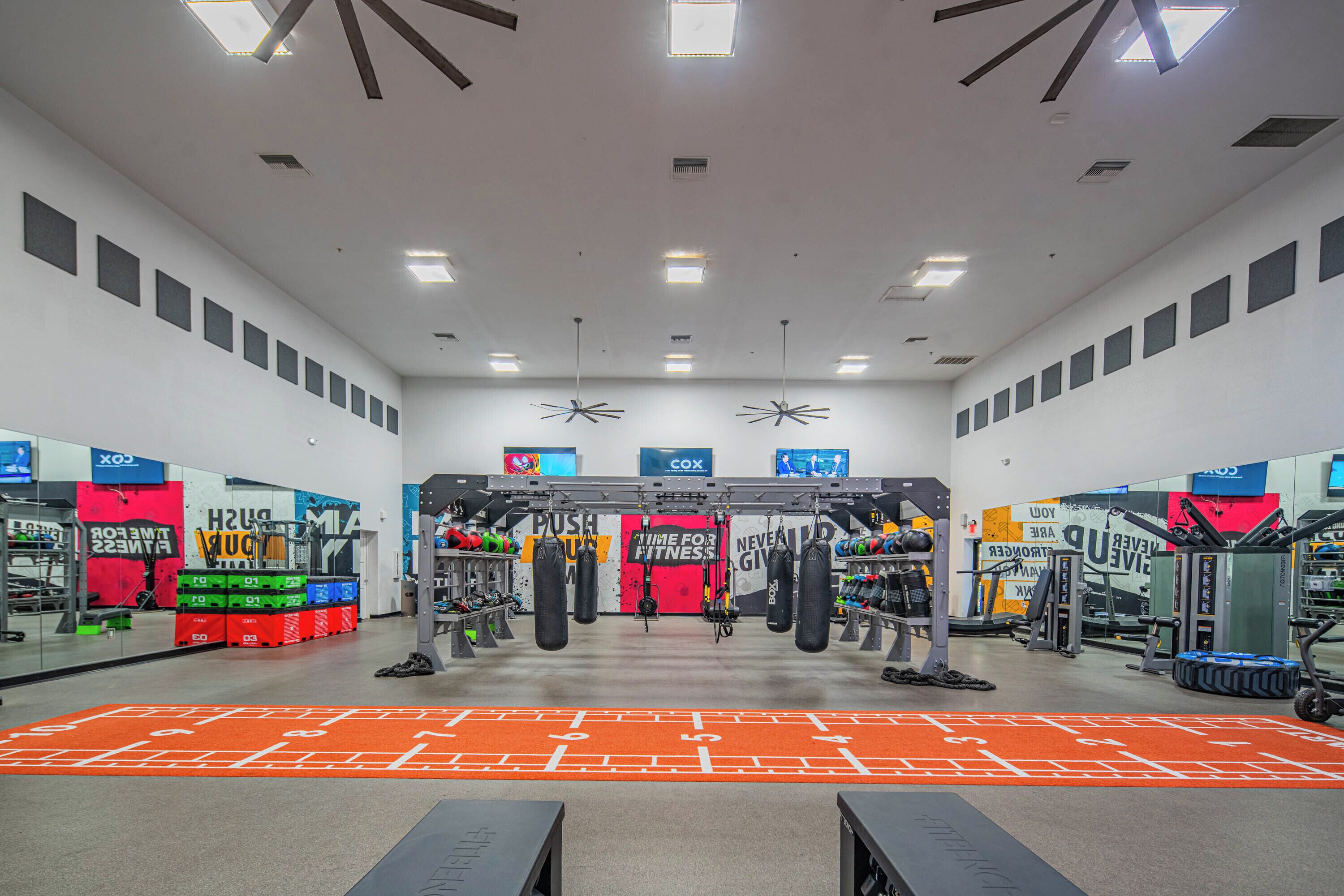 A gym with various exercise equipment, a mirrored wall, and motivational posters.