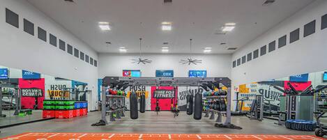 A gym with various exercise equipment, a mirrored wall, and motivational posters.