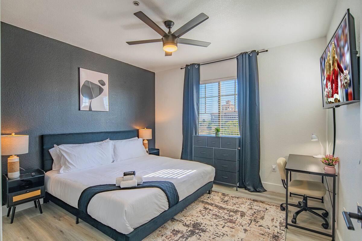 Een moderne hotelkamer met een groot bed, een plafondventilator, een televisie en een bureau met een stoel.