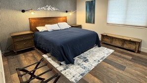 Ein Schlafzimmer mit einem hölzernen Bett, einer Bank, einem Teppich und einer Wandleuchte.