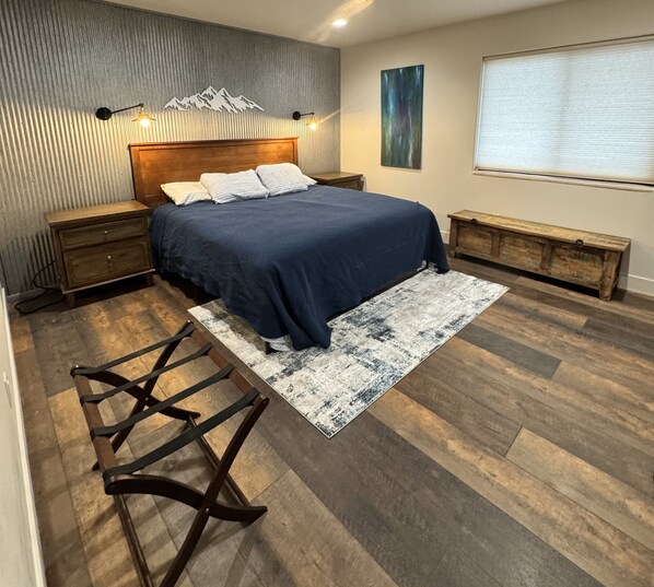 Une chambre à coucher avec un lit en bois, un banc, un tapis et un luminaire fixé au mur.