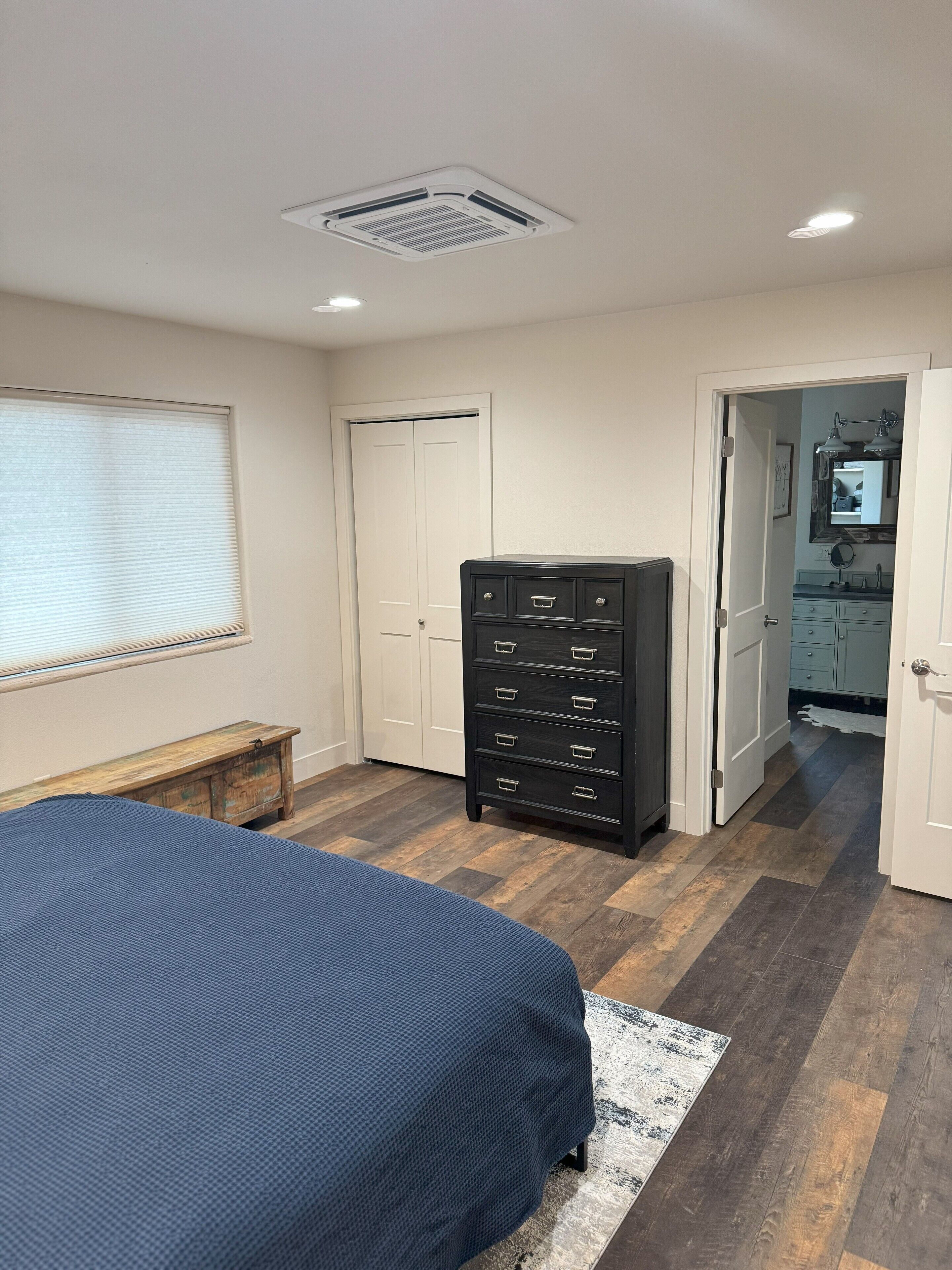 A bedroom with a bed, dresser, and a door leading to a bathroom.