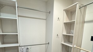 Ein begehbarer Kleiderschrank mit offenen Regalen, einer Kleiderstange und einer Holztür.