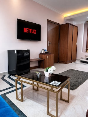 A modern living room with a flat-screen TV, a coffee table, a sofa, and a wooden wardrobe. - Sky Hotel Pyramids View INN (Giza)