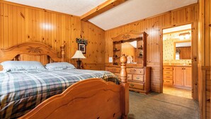 Une chambre aux murs lambrés, avec un lit, une commode et un miroir.