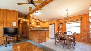 L’intérieur d’une cabane en bois comprend un coin repas, une cuisine et un téléviseur.